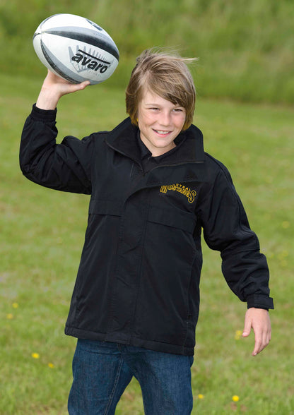 Young boy holding a rugby ball outdoors on a grassy field